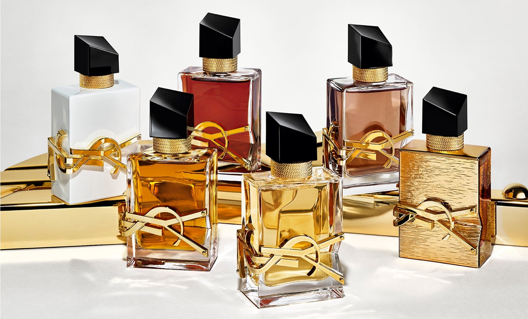 YSL Libre fragrance collection: six bottles in various shades, featuring gold accents, embedded YSL Beauty logo and black caps.