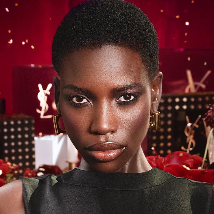 Model featuring the striking Ruby Fizz eyeshadow look from the YSL Holiday collection, set against a decadent YSL Holiday Show scene with light.