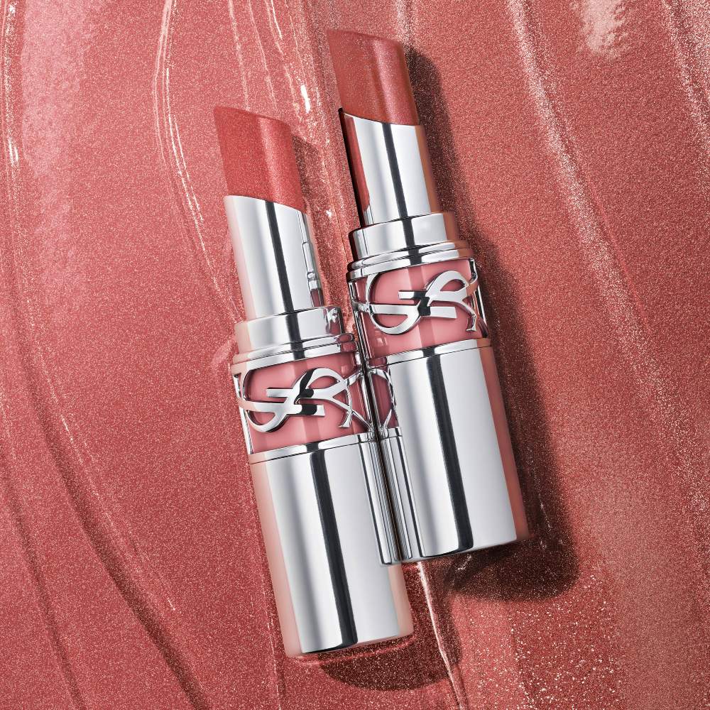 Two YSL LOVESHINE Candy Glaze lipsticks, shades 10 and 215, open
on a shimmery pink textured background.
